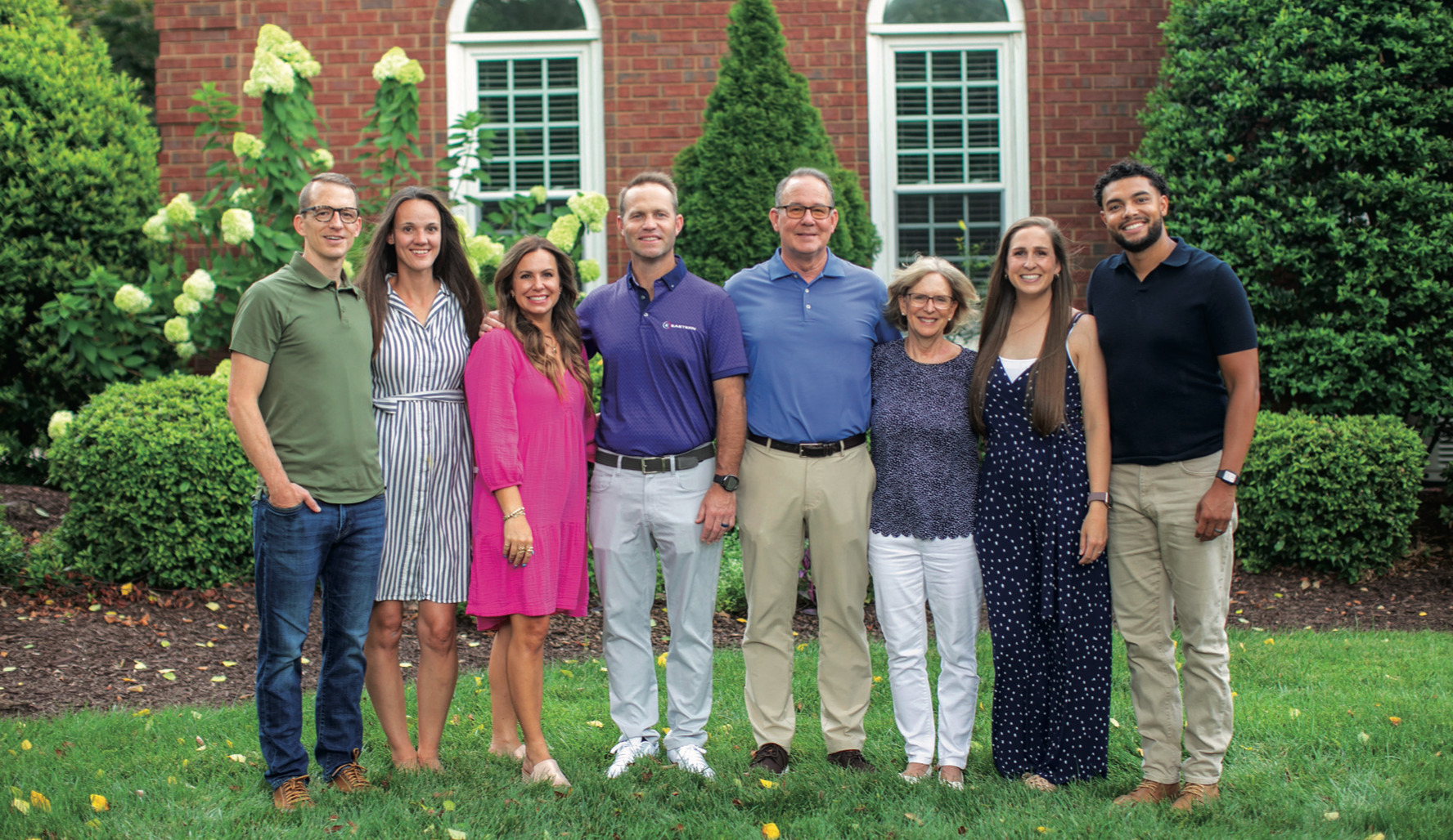 The Miller family, chairs of the Anderson University RISE campaign, standing together on the lawn outside a brick home.
